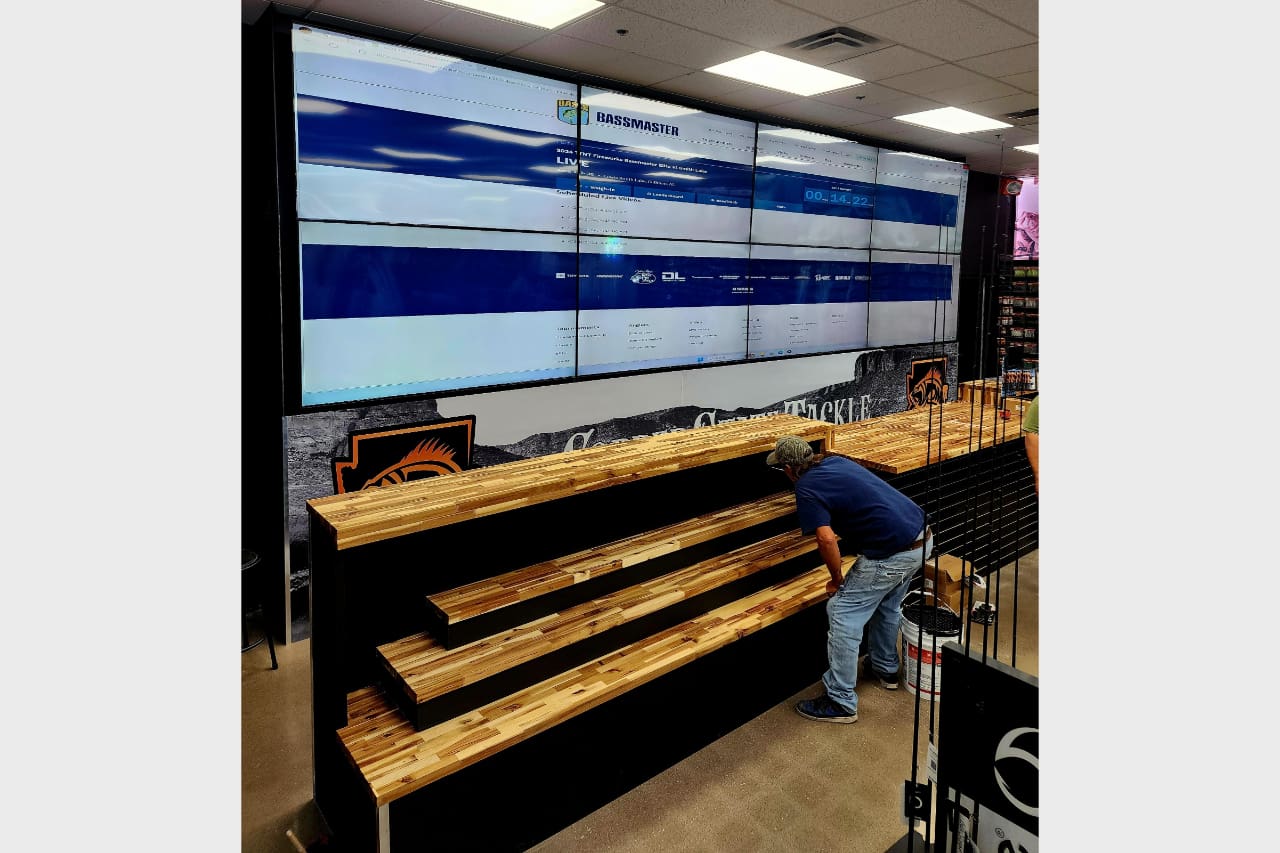 A person arranging baguettes on wooden shelves in a bakery.