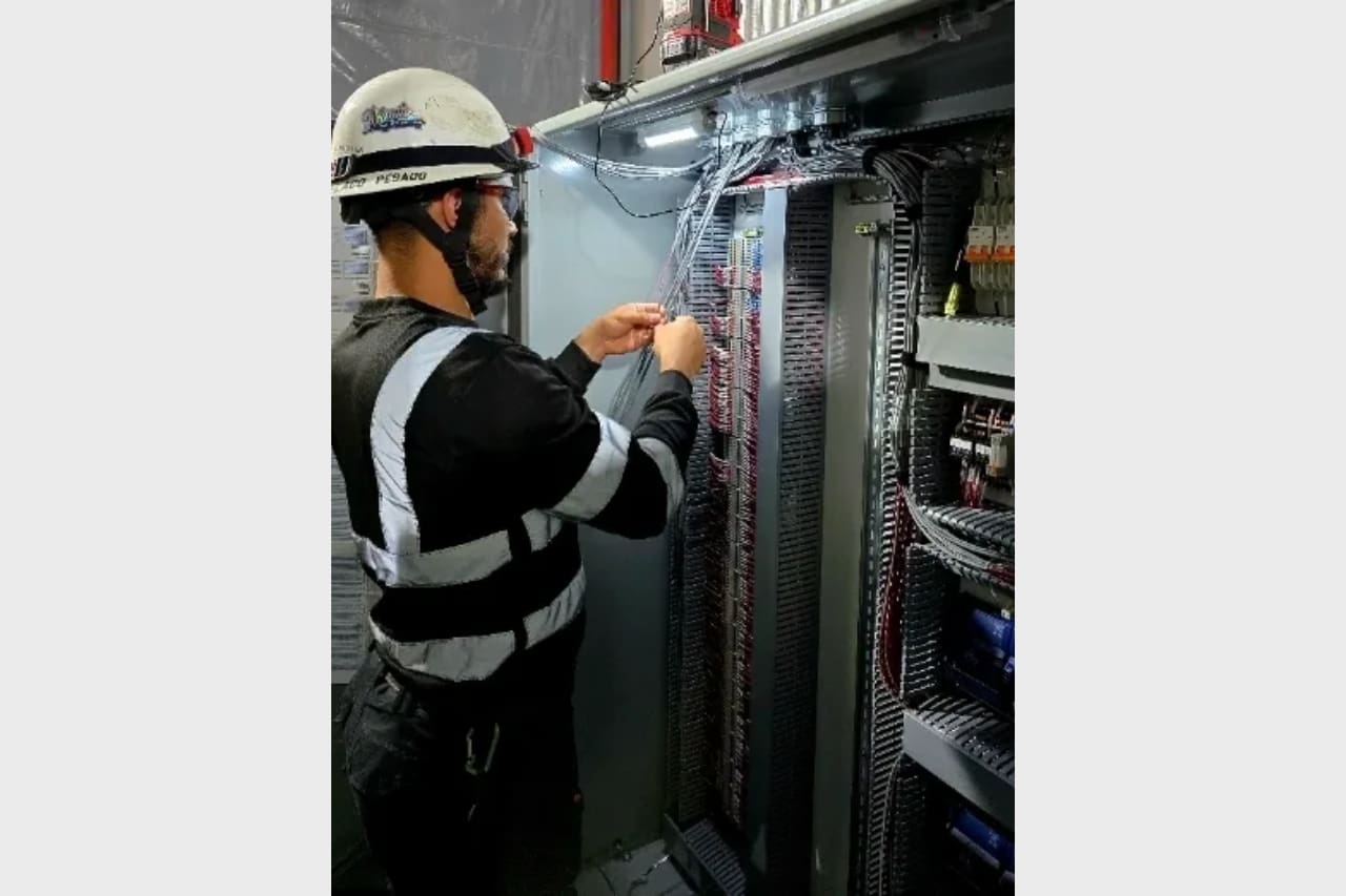 Technician working on electrical panel in safety gear.