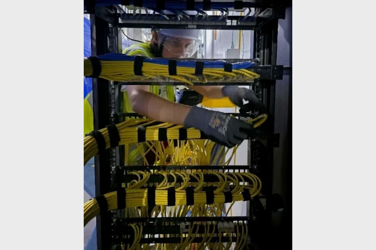 Technician working on a server rack with yellow network cables.
