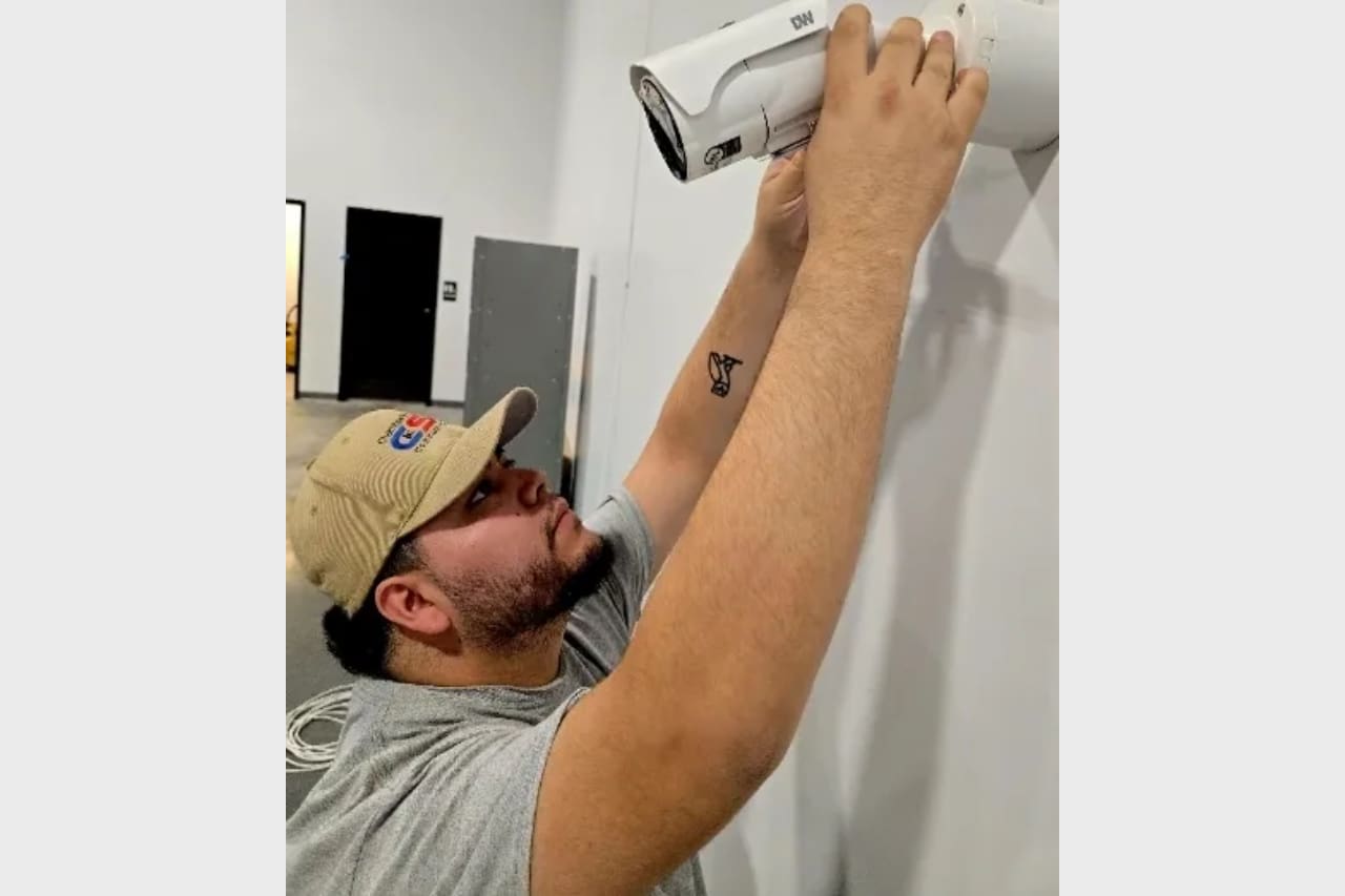 Man installing a security camera on a wall.