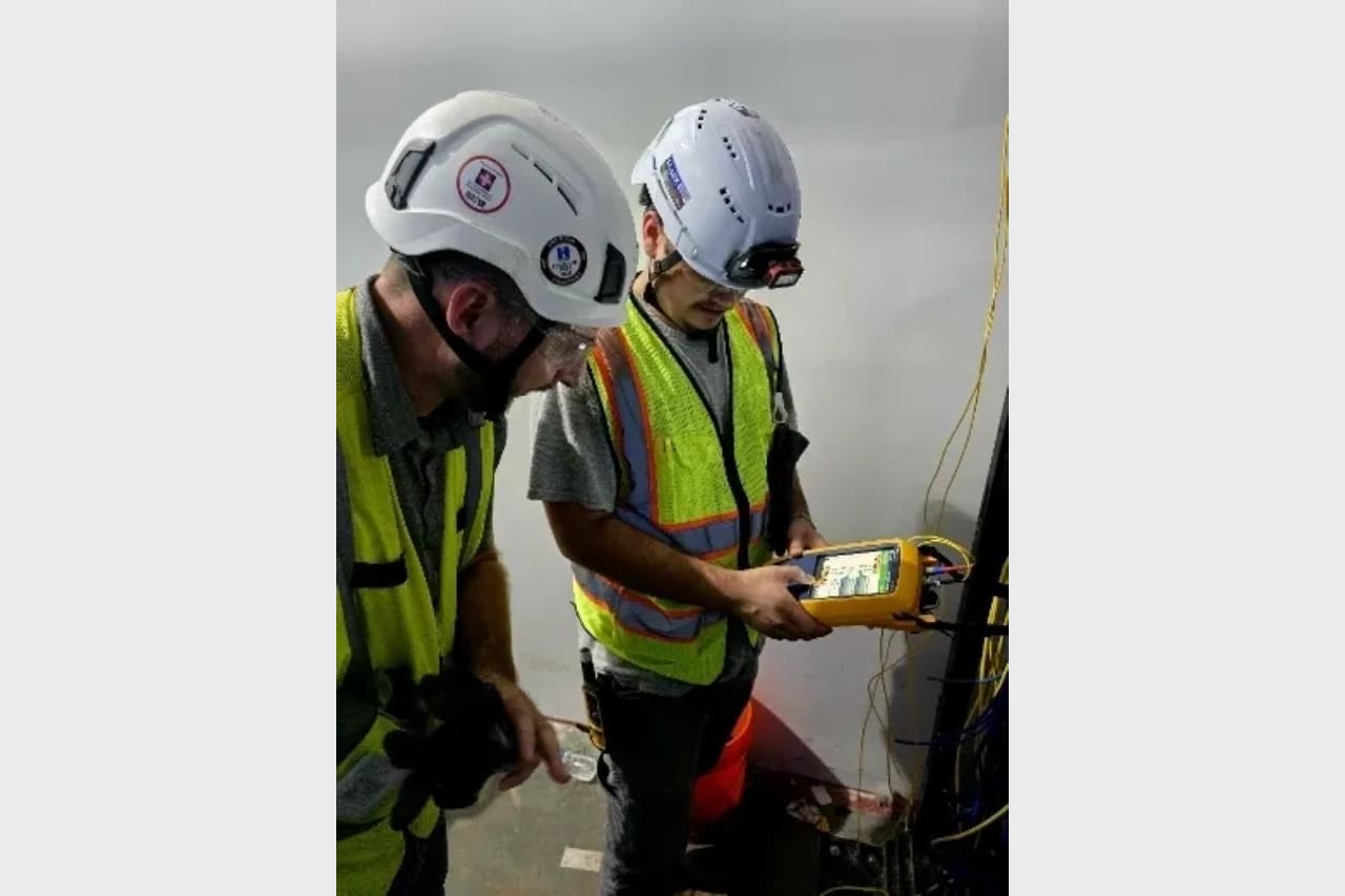 Two construction workers inspecting equipment indoors.